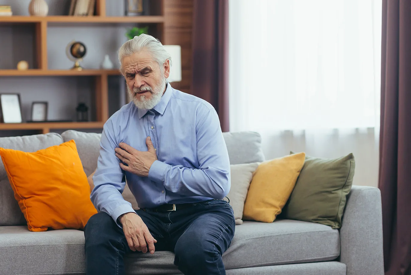 a man sitting on the sofa with his hand on his chest due to acid reflux discomfort. acid reflux treatment in Huddersfield.