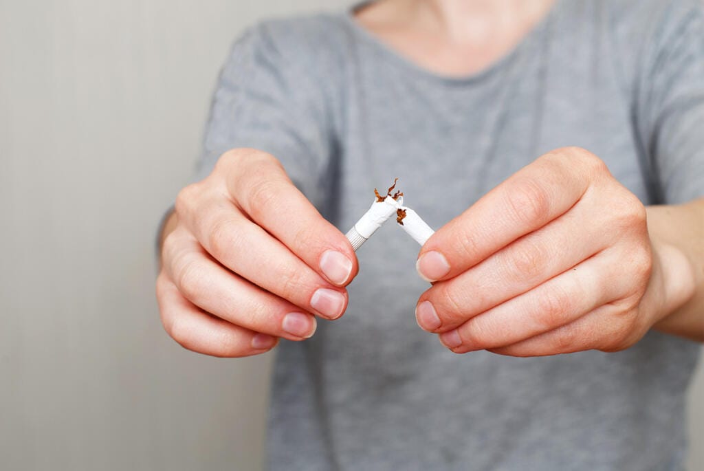 A man breaking a cigarette. NHS Stop Smoking Service in Huddersfield.