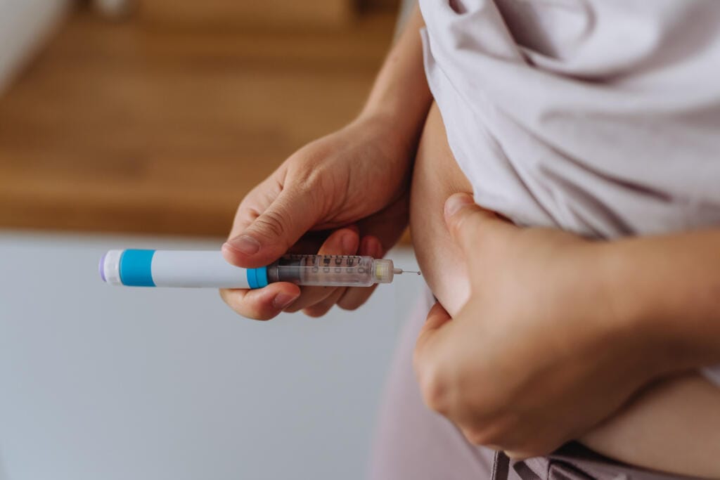 Woman self-administering weight loss injection in abdomen – Weight Loss Injections in Huddersfield"